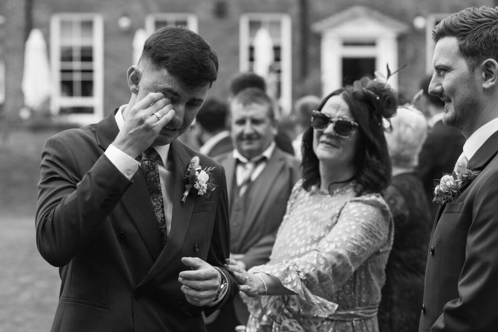 Groom wiping tears from his eye during emotional wedding ceremony outside Stockton House, Shropshire