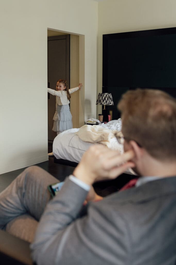 daughter of the groom stops her father, the groom from looking at the bride getting ready by guarding the door as he watches on