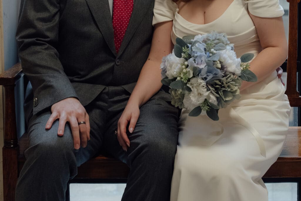 close up of the bride and groom's hands as they sit together waiting for their wedding at Marylebone Town Hall