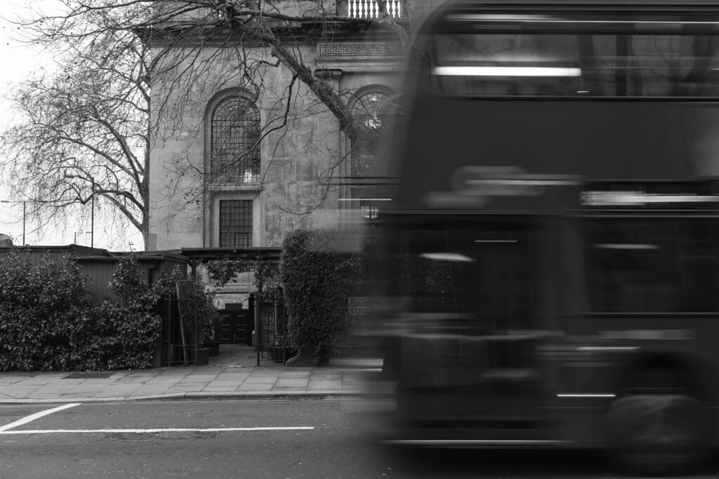 a bus flashes through frame in the foreground of an establishing shot of The Greenhouses in Fitzrovia London