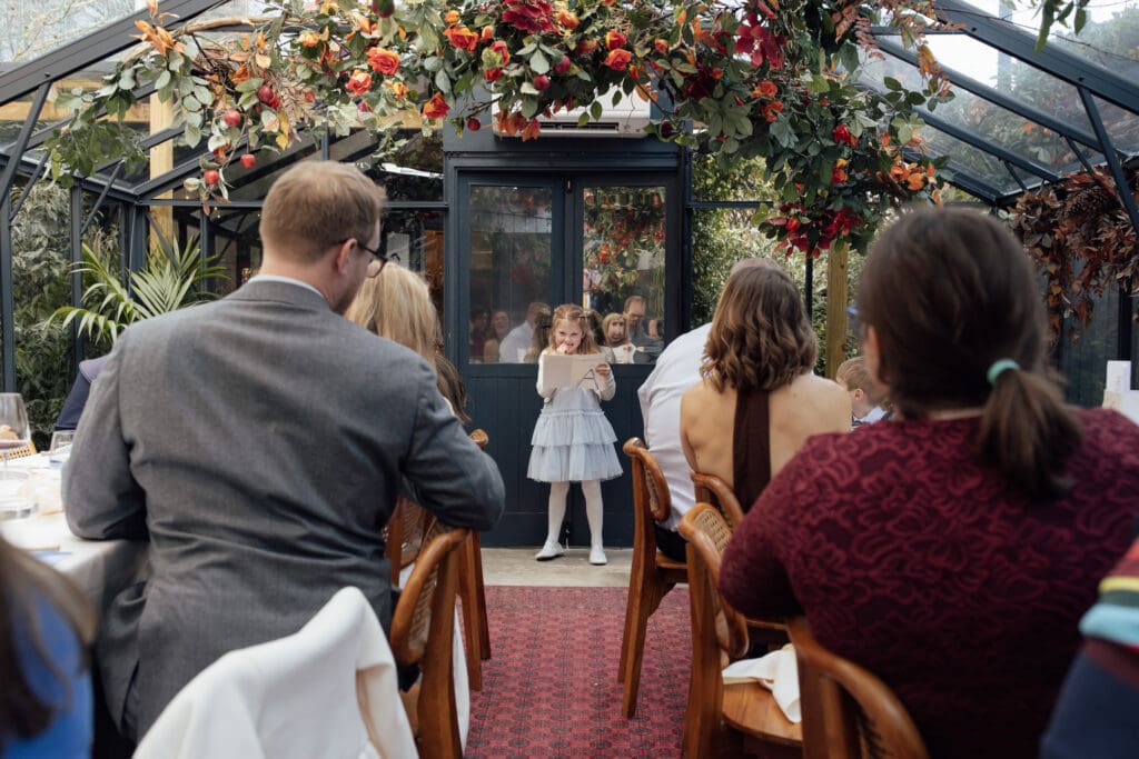 daughter of the groom reads her speech out in front of all the guests after dinner at the greenhouses in London