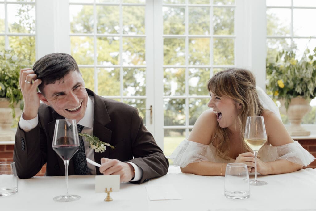 Bride and groom seated at top table laughing together during wedding speeches at Stockton House, Shropshire
