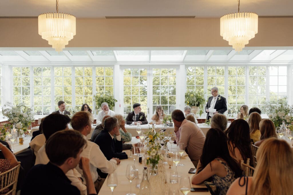 Guests seated at long tables during wedding breakfast while speech is given at Stockton House, Shropshire