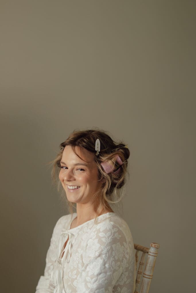 Bride smiling during morning preparations with hair in rollers at Stockton House wedding in Shropshire