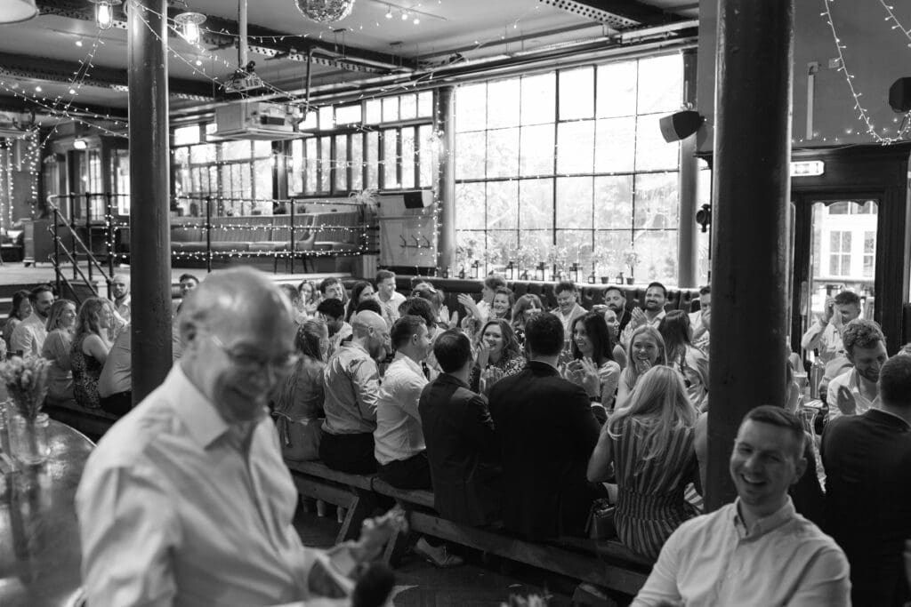 Wedding guests laughing and applauding during speeches at The Depot wedding reception.