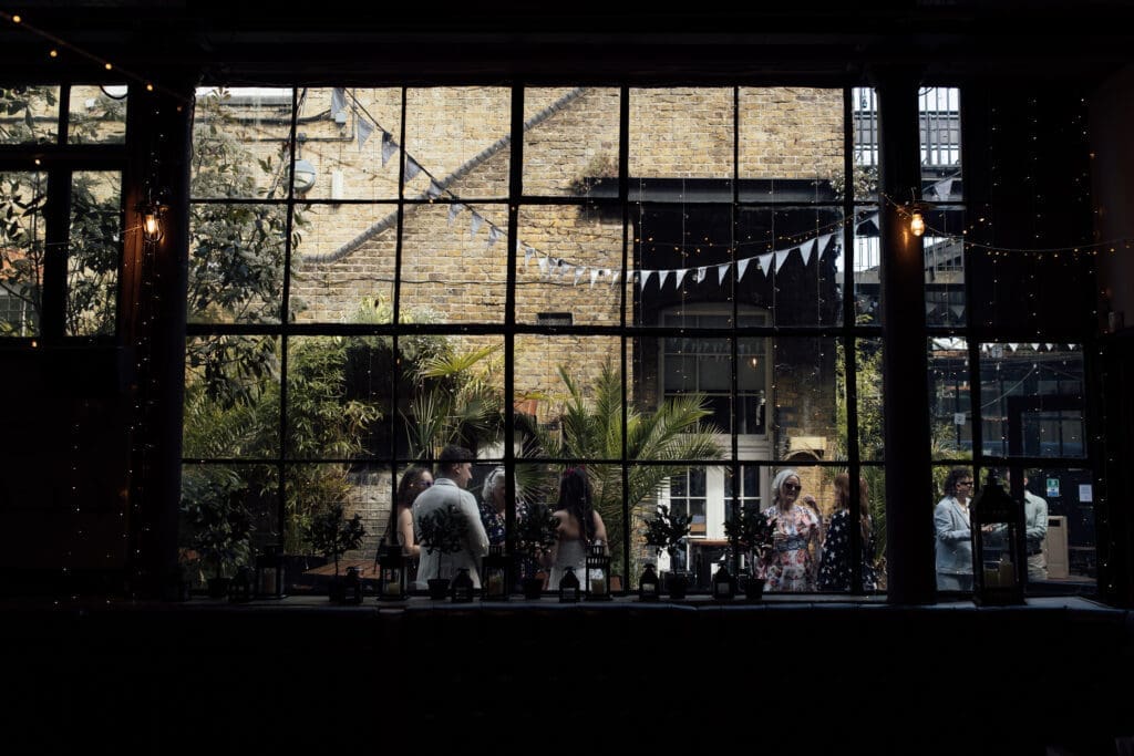 Guests chatting in The Depot courtyard viewed through the venue's industrial warehouse windows.
