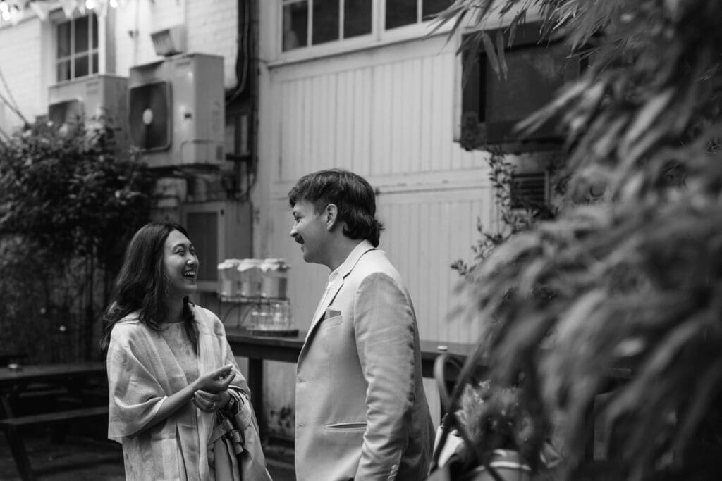 Wedding guests laughing together in The Depot courtyard during drinks reception.