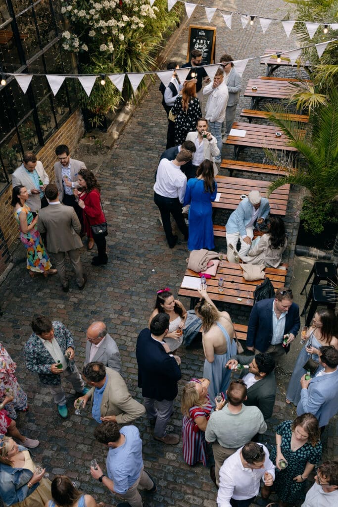 Guests chatting in The Depot courtyard during a relaxed wedding celebration in London.